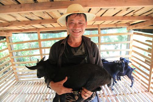 图为文昌市冯坡镇乐大村的贫困户符国业抱着边防官兵送来的黑山羊