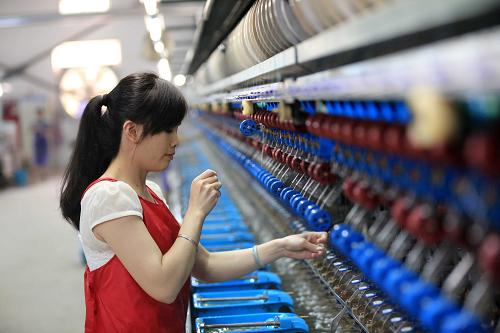 6月12日，广西融安县一家企业的工人在蚕丝加工生产线上工作。