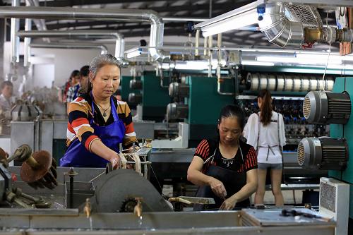 6月12日，广西融安县一家企业的工人在蚕丝加工生产线上抽丝。
