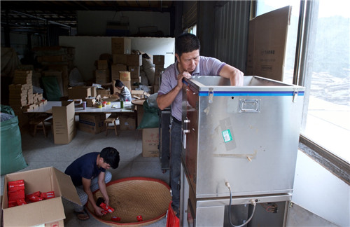 10月9日，王明江（右）与长子王有长在茶厂进行茶叶包装。