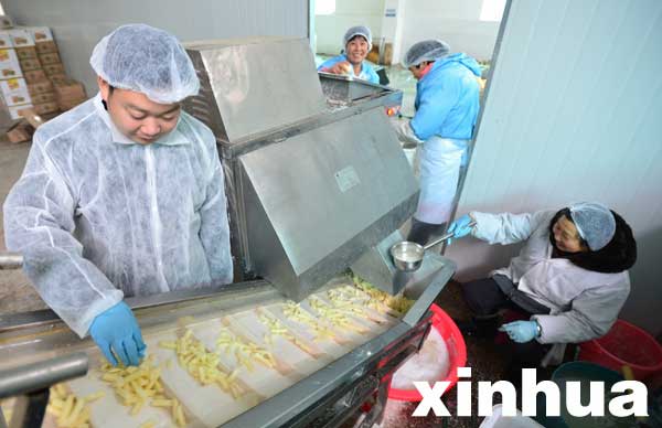 3月3日，汤雄（左）在工厂薯条生产线上工作。